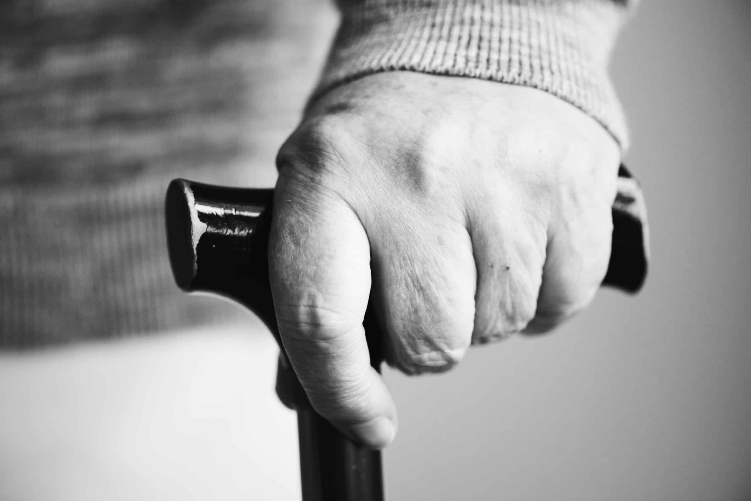 closeup elderly hand holding walking stick scaled